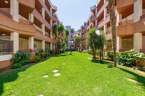 A courtyard with a central lawn, surrounded by multi-story buildings with balconies and windows. - Beachfront apartment in Vilafortuny (Cambrils)