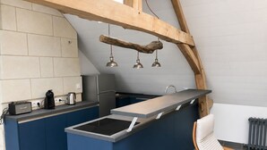 Una cucina moderna con isola integrata, macchina del caffè, bollitore e frigorifero.