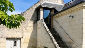 Un edificio in pietra con una terrazza in legno, una scala e un tavolo con sedie.