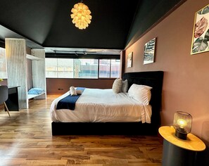 Et moderne soveværelse med en stor seng, en hængende lampe og billedkunst på væggene.