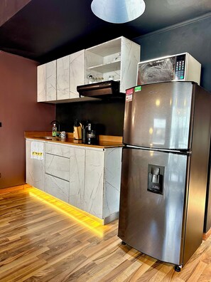 Eine moderne Küche mit Edelstahlkühlschrank, Marmor-Schränken, einer Holzarbeitsplatte und einem eingebauten Backofen.