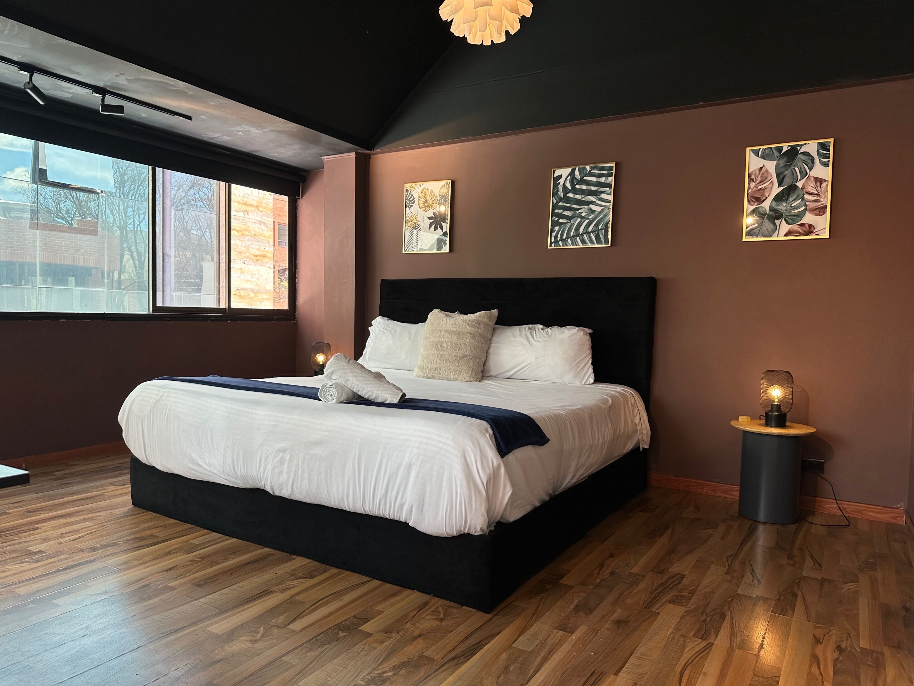 Une chambre moderne avec un grand lit, un plancher en bois et des œuvres d’art accrochées aux murs.