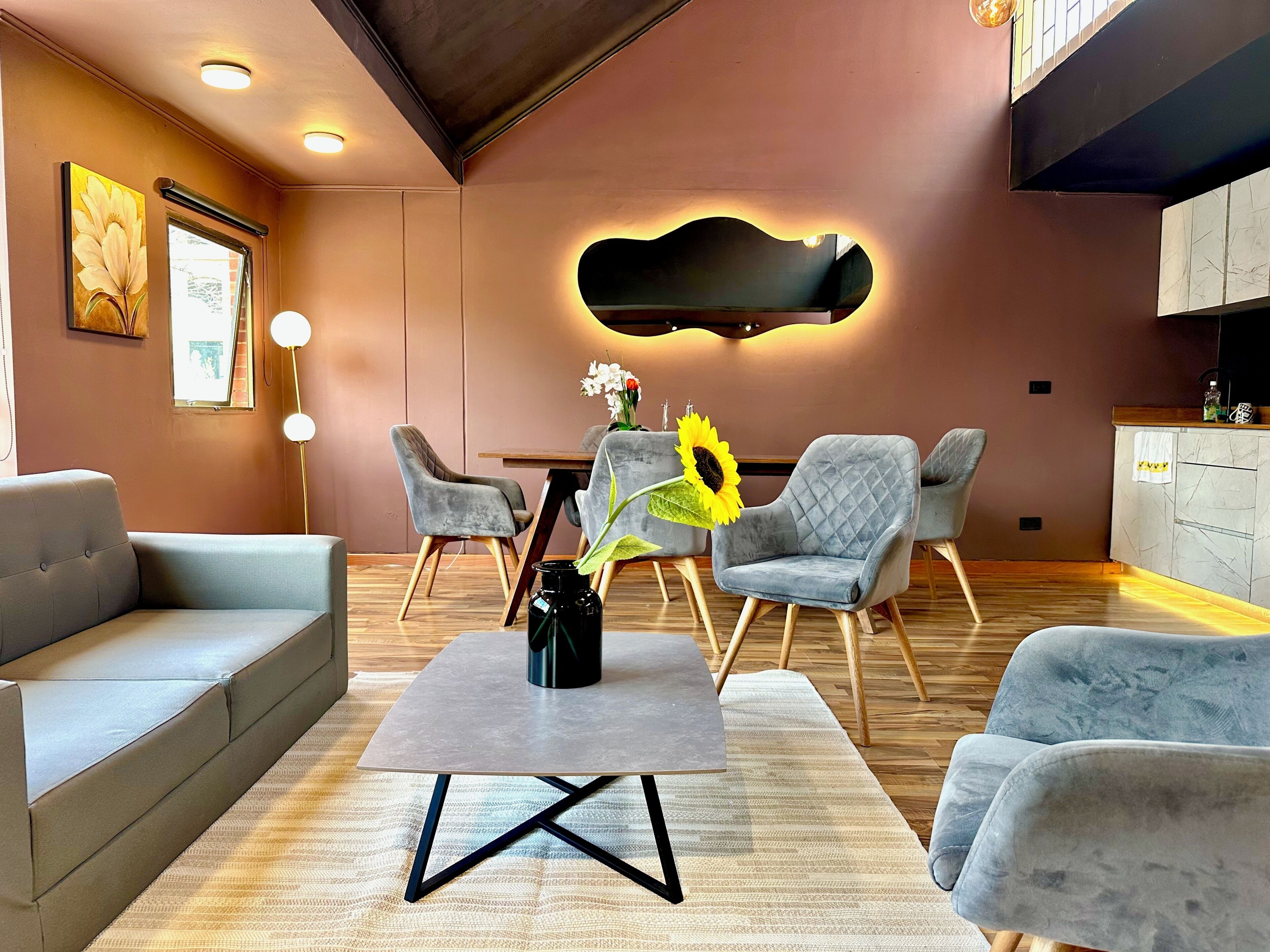Ein modernes Wohnzimmer mit einer Couch, Sesseln, einem Couchtisch und einer Wandleuchte.