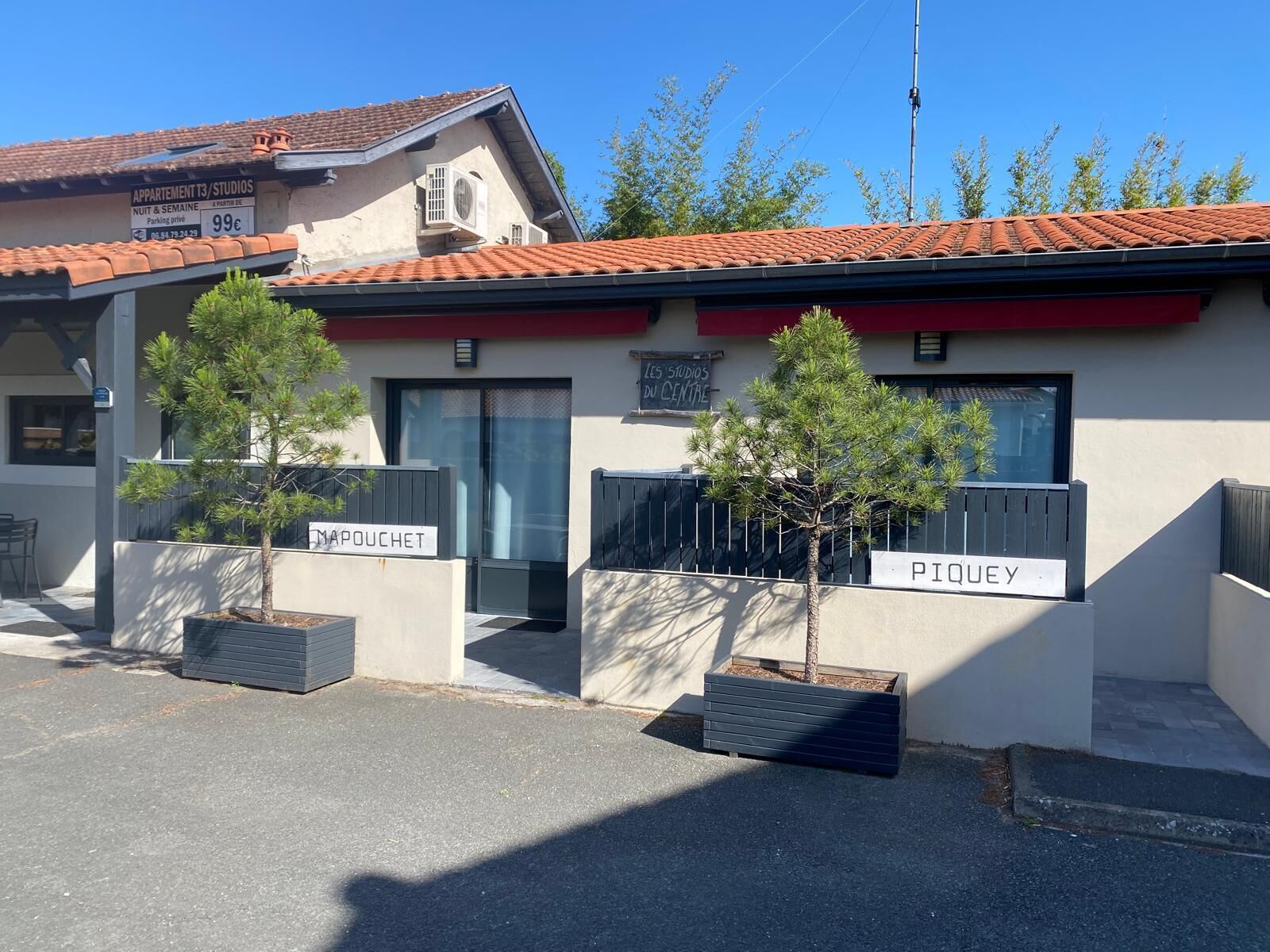 A building with a sign indicating 'APPartement T3/STUDIOS' and 'Nuit & Semaine' parking availability.
