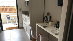 A compact kitchen with a dining area, a coffee maker, and a TV mounted on the wall. - Les Studios du Centre Buch (La Teste)