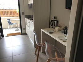 Una cocina compacta con comedor, cafetera y televisor montado en la pared.