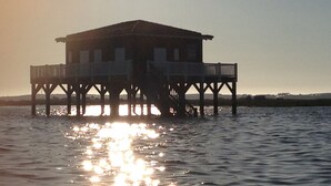 A wooden pier structure with a flat roof and multiple levels, extending over a body of water. - Les Studios du Centre Buch (La Teste)