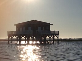 A wooden pier structure with a flat roof and multiple levels, extending over a body of water.