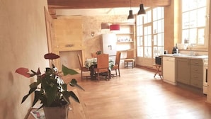 Uma cozinha espaçosa com piso de madeira, uma área de jantar com cadeiras e um vaso de planta.