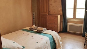 Quarto com cama, cômoda, radiador e janela com cortinas.