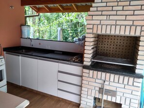 A kitchen with a brick oven, a sink, and a window overlooking greenery. - Mini Club with Biribol (a Brazilian beach volleyball game) (Bertioga)