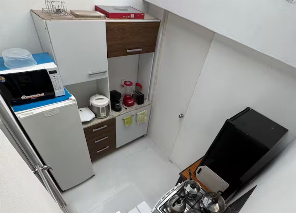Una cuina petita amb microones, cafetera i nevera.