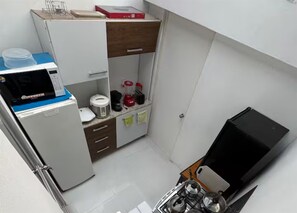 A compact kitchen with a microwave, coffee maker, and a small refrigerator.