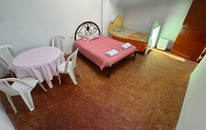 A small room with a bed, a table with chairs, a heater, and a mirror.