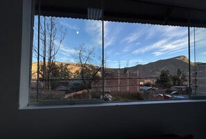 A window with a view of a mountainous landscape, a clear sky, and a crescent moon.