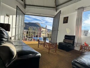 Ein Zimmer mit einer schwarzen Ledersofa, einem Holzstuhl und einem kleinen Tisch mit einer roten Figur.