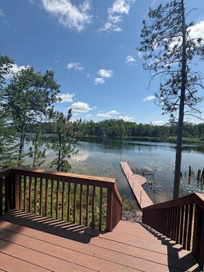 Una terraza de madera con vistas a un lago rodeado de árboles.