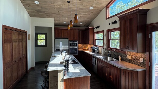 A spacious kitchen with wooden cabinets, a central island, and pendant lighting.