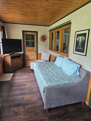 A bedroom with a bed, a television, a wooden cabinet, and a mirror.