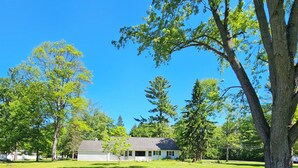 A grassy yard with a large tree and a house in the background. - Snowmobile Sanctuary in the Charming Village of Crivitz (Crivitz)