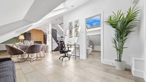 A modern loft-style room with a dining area, a large potted plant, and a staircase leading to an upper level. - Luxe Farringdon Apartments By Stay Smart (London)