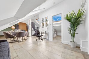 Ein stilvolles Loft mit Essbereich, einer großen Pflanze und einer Treppe zu einer erhöhten Ebene.