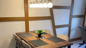 A modern dining area with a wooden table, black chairs, and a hanging light fixture.