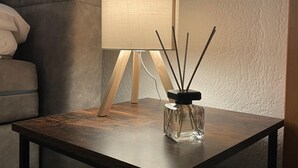 A small wooden table with a glass candle holder and a lamp on it.