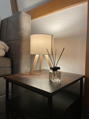 Ein kleiner Holztisch mit einem Glaslaternenfuß und einer Lampe darauf.