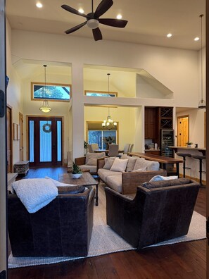 A spacious living area with a high ceiling fan, a chandelier, and a view of the outdoors through a large window. - Fabulous 5BR Cabin in Torreon with Hot Tub & Huge Deck (Show Low)