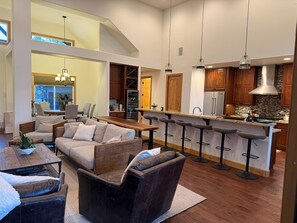 A modern kitchen with wooden cabinets, a stainless steel refrigerator, and a bar area with stools. - Fabulous 5BR Cabin in Torreon with Hot Tub & Huge Deck (Show Low)