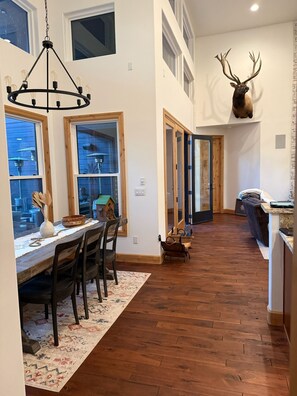 A spacious kitchen with a wooden floor, a dining area with a table and chairs, and a large deer head mounted on the wall. - Fabulous 5BR Cabin in Torreon with Hot Tub & Huge Deck (Show Low)