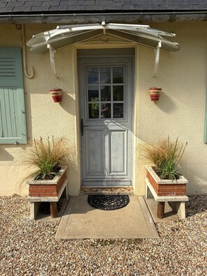A house with a white door, two potted plants, a small porch, and a gravel driveway. - Family home in the countryside, 25 km from Rouen (Auzouville-sur-Ry)