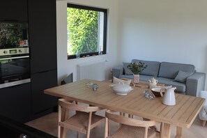 A modern kitchen with a wooden table, chairs, and a view of greenery outside. - Family home in the countryside, 25 km from Rouen (Auzouville-sur-Ry)