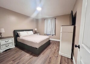 Une chambre à coucher avec un lit, des tables de chevet, une commode et une porte.