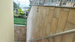 Una escalera de piedra con barandilla de metal que conduce a un área cerrada con vistas a zonas verdes.