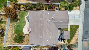 Vue aérienne d’une propriété résidentielle comprenant un grand bâtiment à toit plat, une cour clôturée et une végétation luxuriante.