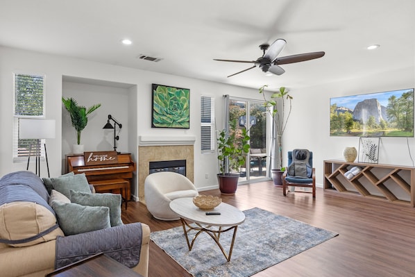 A living room with a piano, a sofa, a coffee table, and a television.