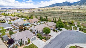 A suburban neighborhood with detached houses, a paved driveway, and a mountain backdrop.
