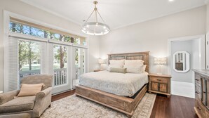 A bedroom with a large bed, a chair, a nightstand, and a mirror. - Callawassie Island Beautiful 3BR/3BA Retreat Free Golf, Riverfront Pools (Okatie)
