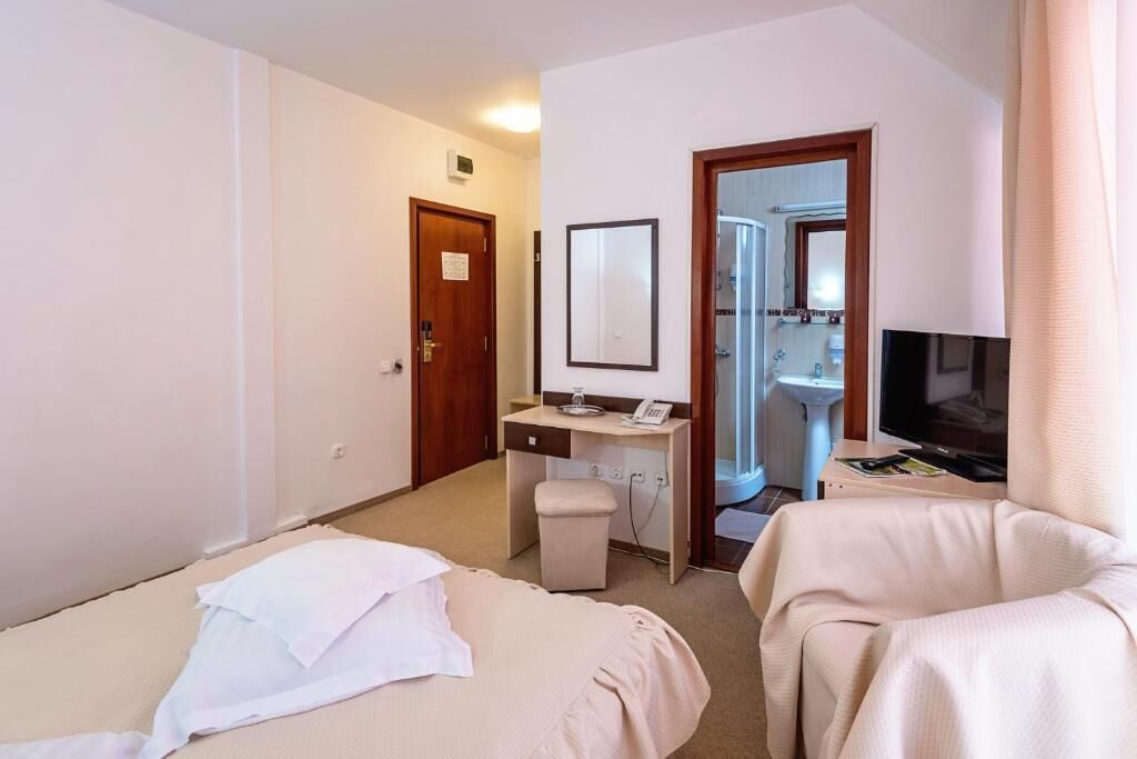 Ett hotellrum med två sängar, ett skrivbord, en tv och ett badrum som syns genom en öppen dörr.
