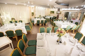 A hotel dining area with multiple round tables, green chairs, and white tablecloths. - SUIOR RESORT  (Baia-Sprie)
