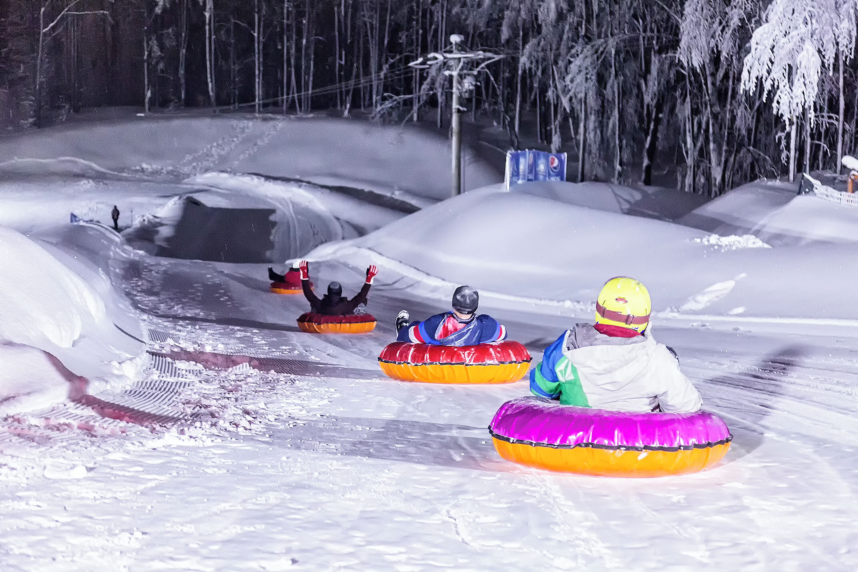 A snowy landscape with people on snow tubes.