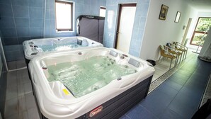 A spa room with two hot tubs, a window, and a door.