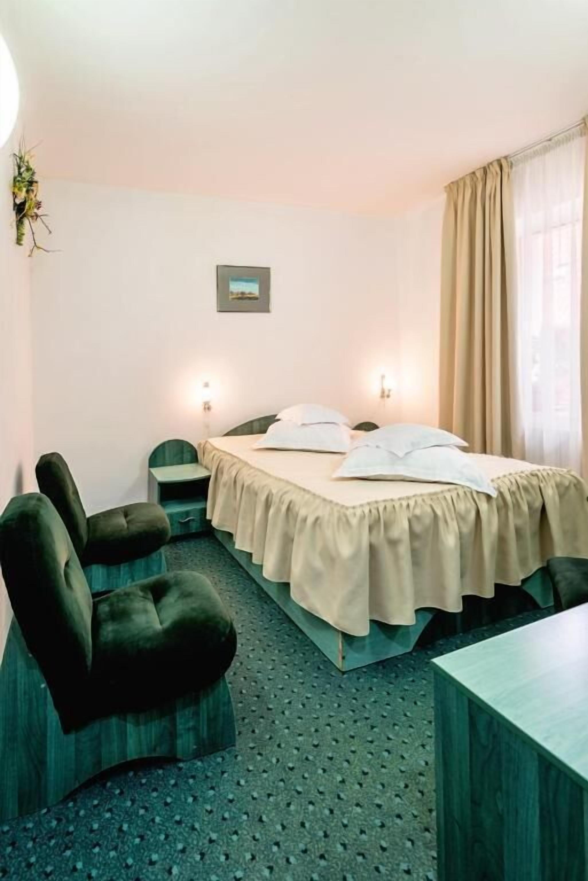 A hotel room with a bed, two bedside tables, a chair, and a desk.