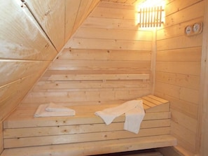 A sauna with wooden walls and benches, a light fixture, and two control panels. - SUIOR RESORT  (Baia-Sprie)