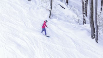 A person snowboarding down a snowy slope with trees on the side.