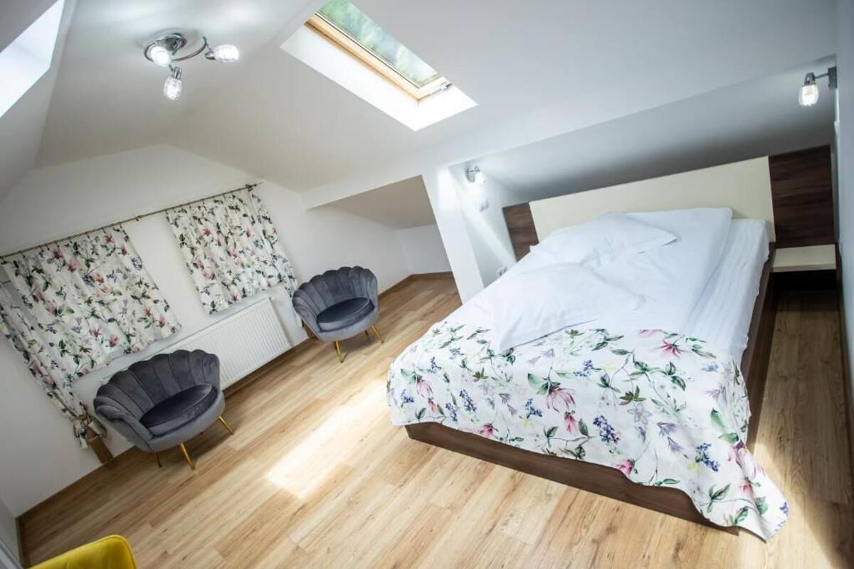 Une chambre à coucher avec un lit, deux chaises, une lucarne et une fenêtre.