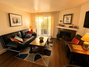 Ein Wohnzimmer mit einer schwarzen Ledersofa, einem Holztisch, einem Kamin und einem Fernseher.