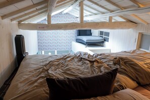 Ein Schlafzimmer mit Bett, Schreibtisch und einem Fenster mit gemusterten Vorhängen.